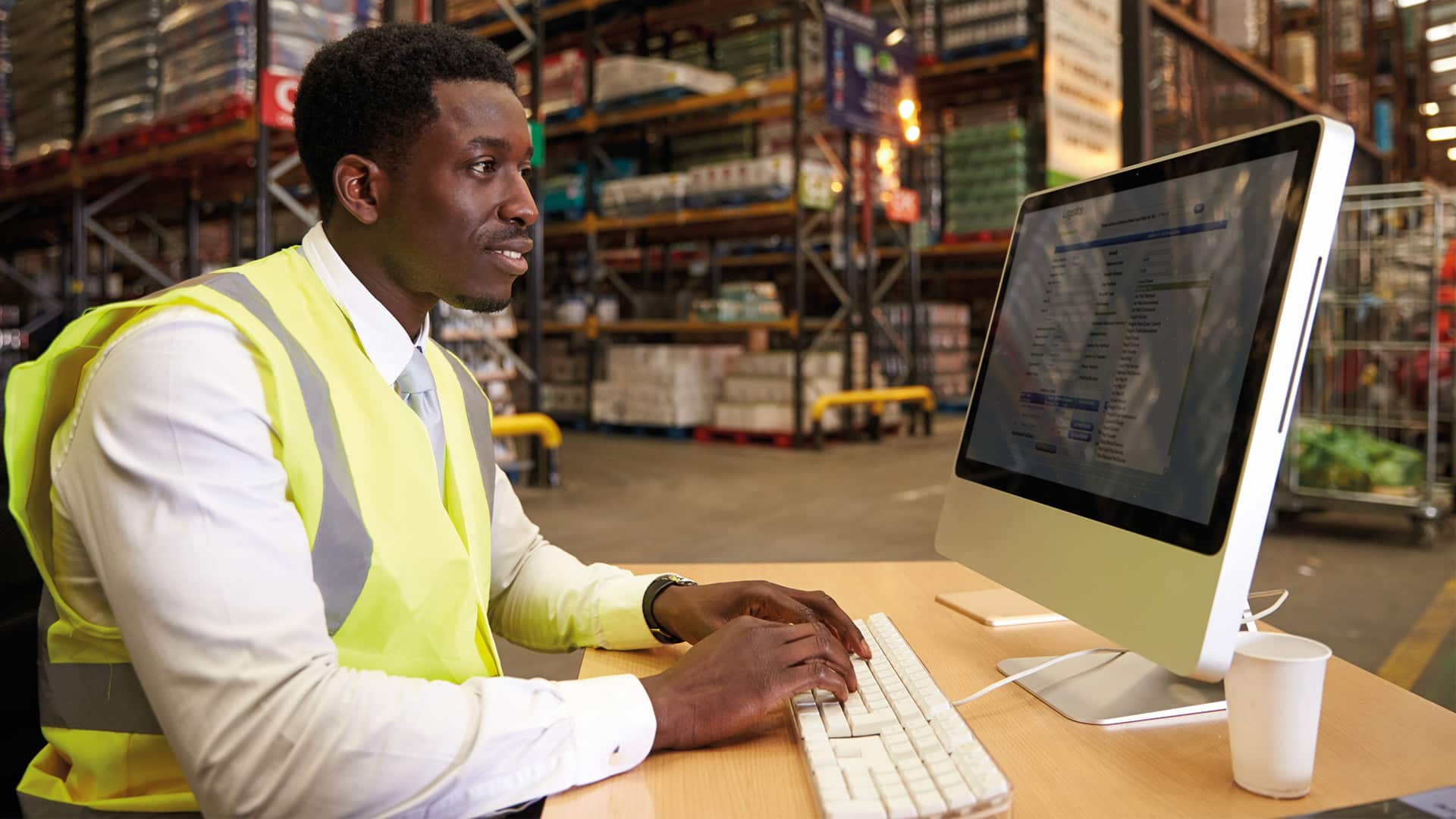 A photo of a man in a high-vis jacket on a computer.