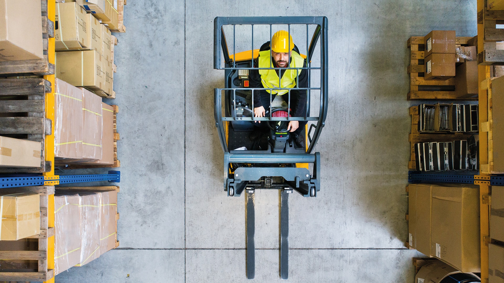 A photo of a man in a forklift looking up at the camera.
