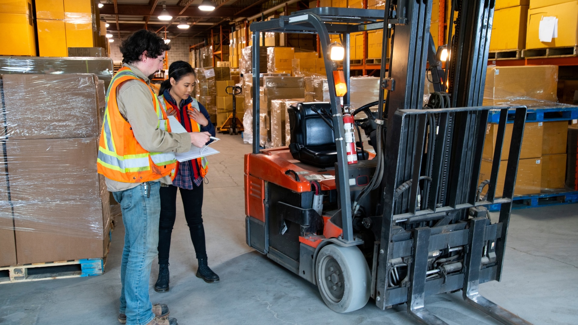 A photo of two people in high-vis jackets doing forklift training.