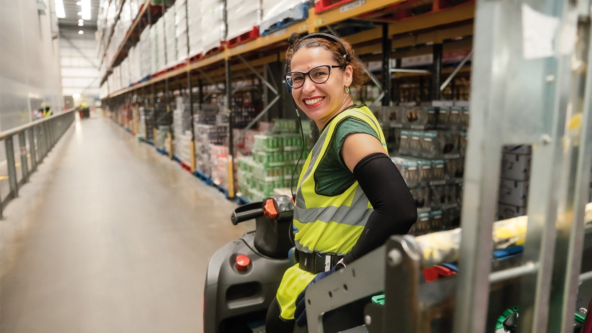 A woman in a forklift at a warehouse.